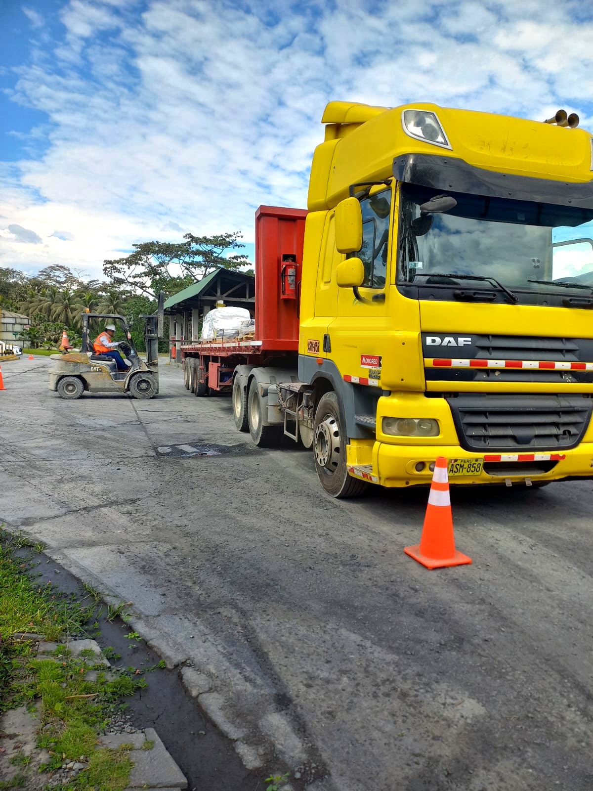 Tracto DAF CF amarillo de TCA con plataforma en operación de carga